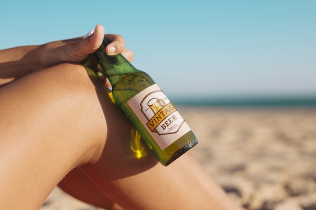Woman with beer bottle mockup at the beach Free Psd